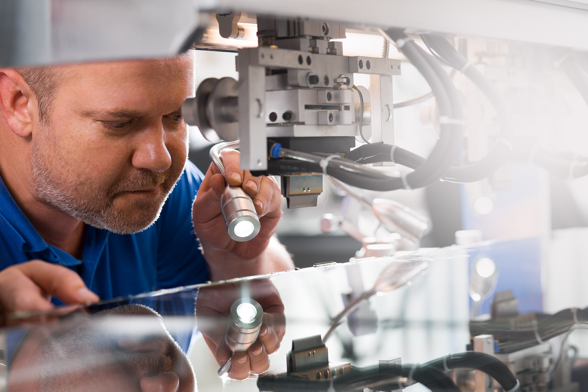 Techniker inspiziert eine Maschine mit einer Taschenlampe, konzentriert sich auf Details bei der Arbeit.